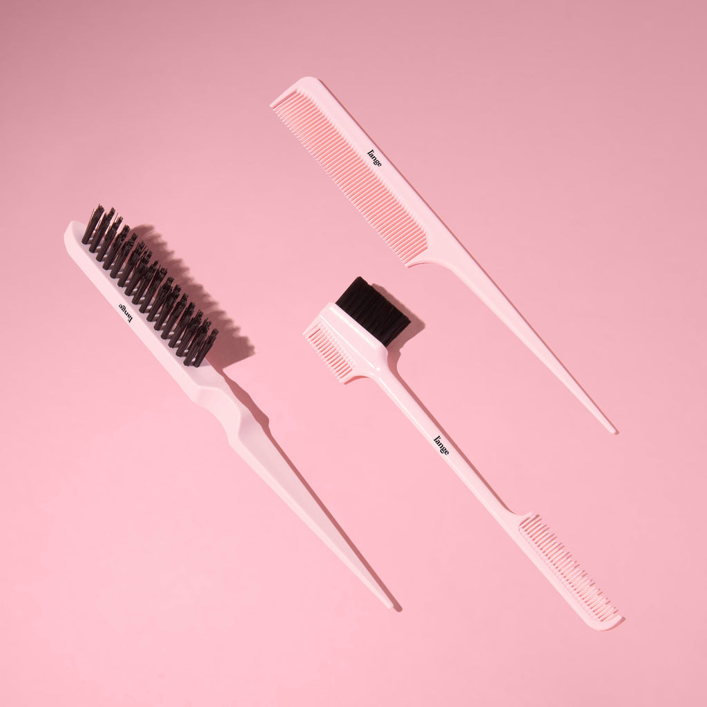 Black L’ange carbon fiber combs and brushes arranged on a pink background.