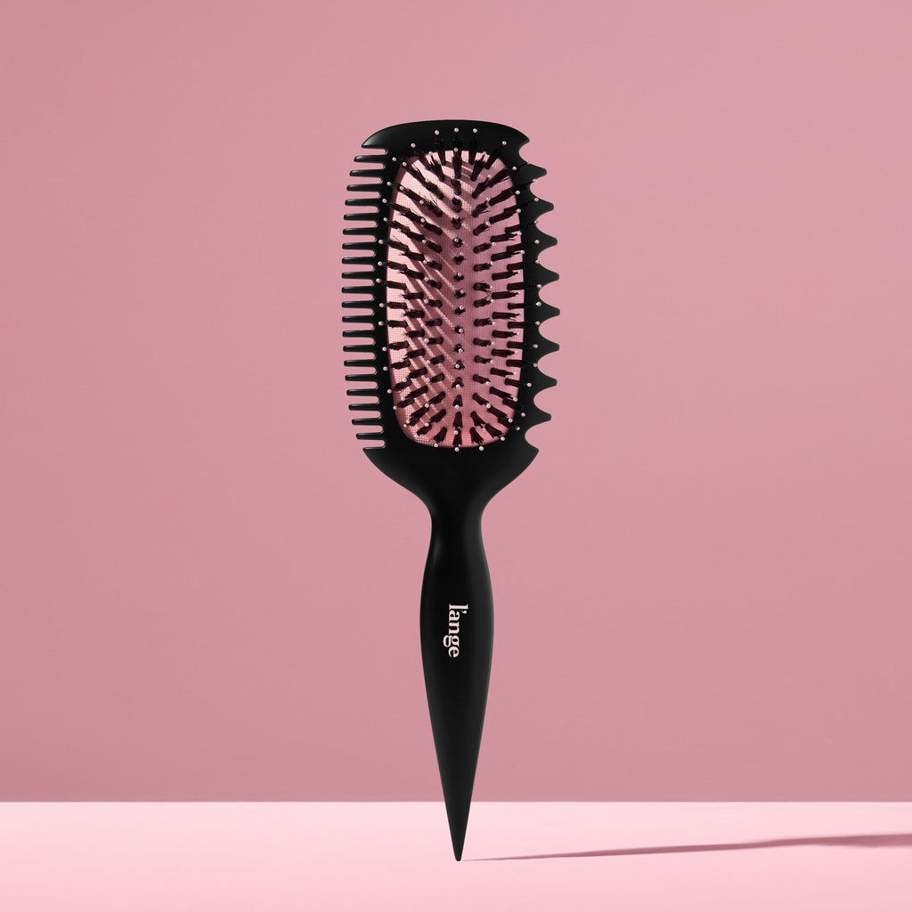 L’ange Curl Sculptor brush standing upright against a pink backdrop