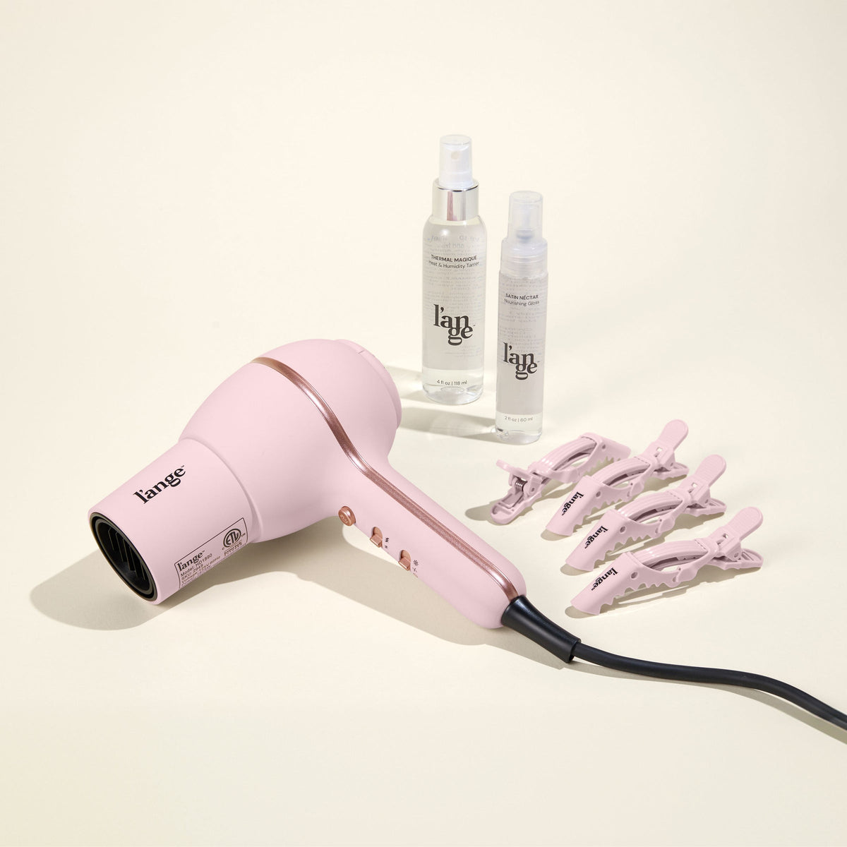 Hot Stuff Blowout Set, featuring a Blush Hot Stuff dryer, Alligator Clips, Thermal Magique, and Satin Nectar, displayed on a beige background