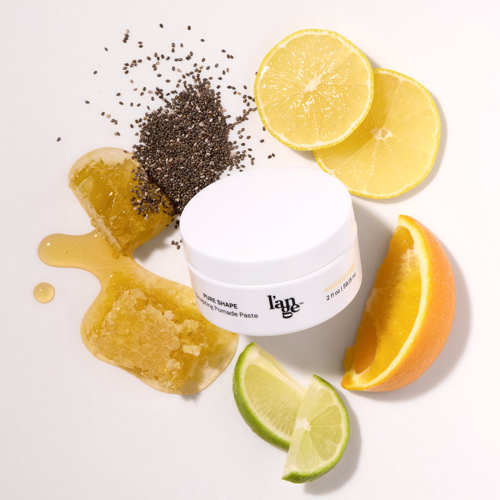 L’ange Pure Shape Sculpting Pomade Paste surrounded by citrus slices, honey, and chia seeds.