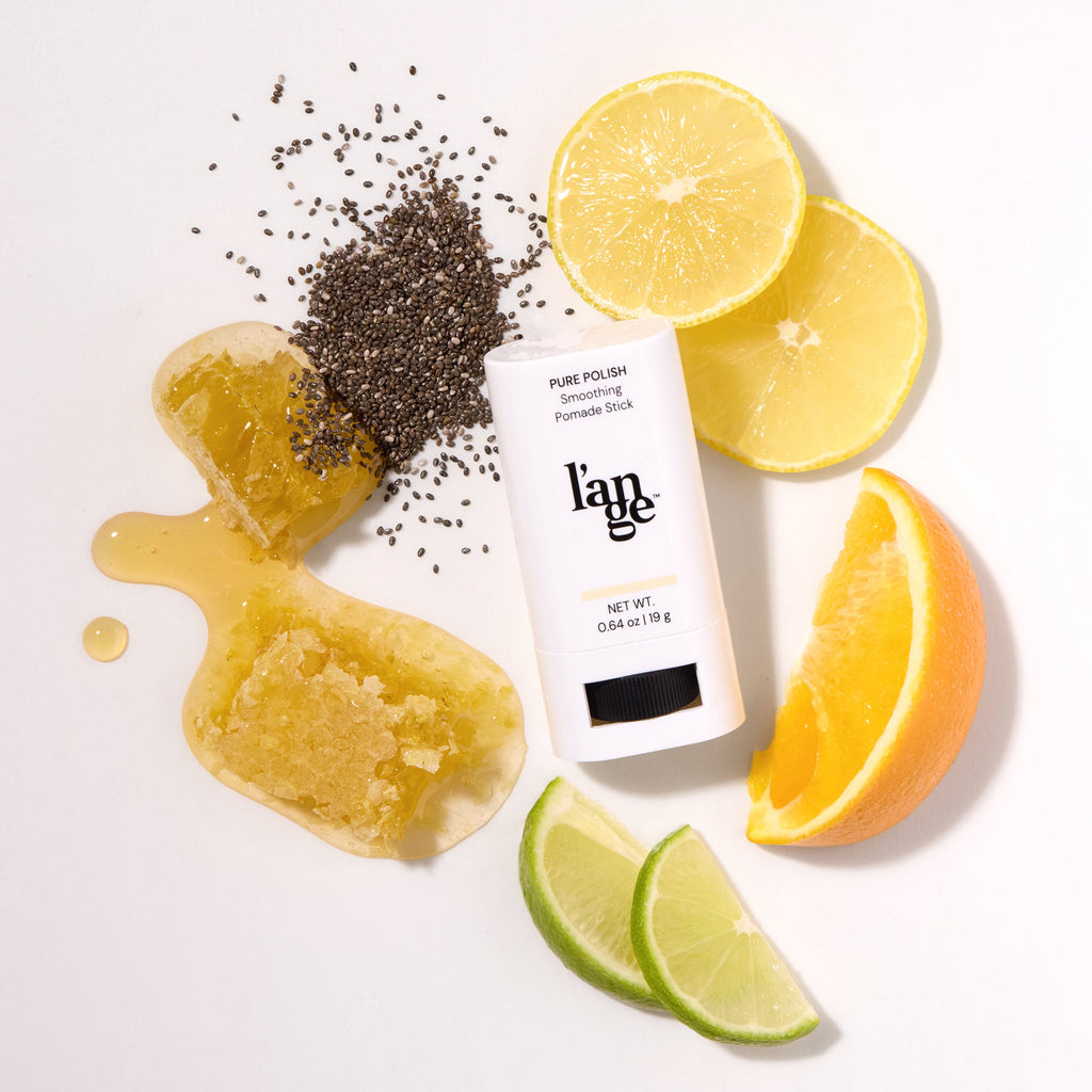 L’ange Pure Polish Smoothing Pomade  Stick surrounded by citrus slices, honey, and chia seeds.