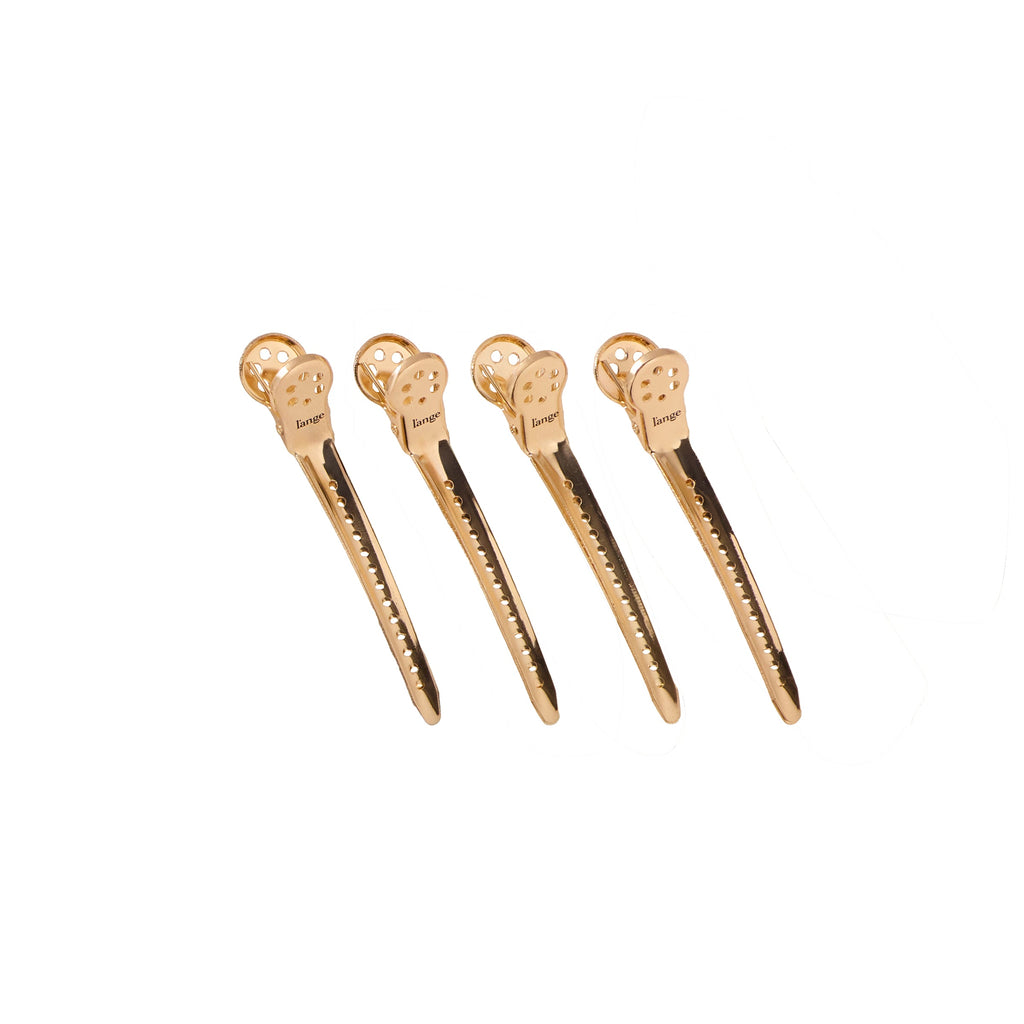 Four gold precision metal hair clips on a white background.