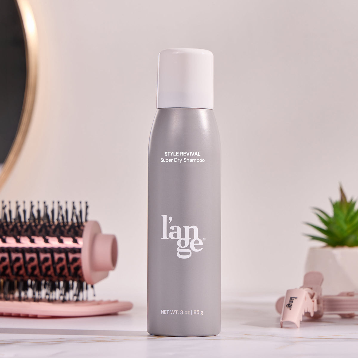 A bottle of Style Revival on a vanity with different L'ange products around it. 