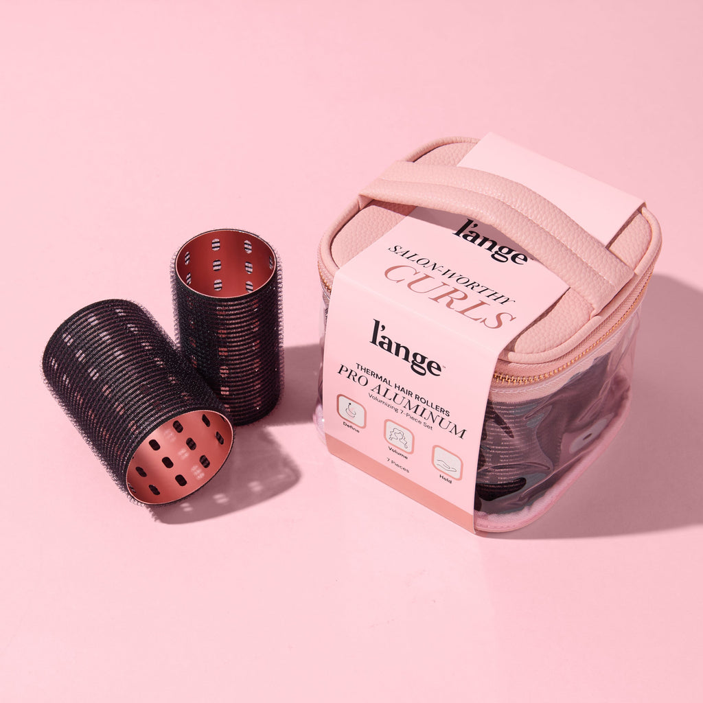 A collection of black thermal hair rollers and case, arranged on a pink background