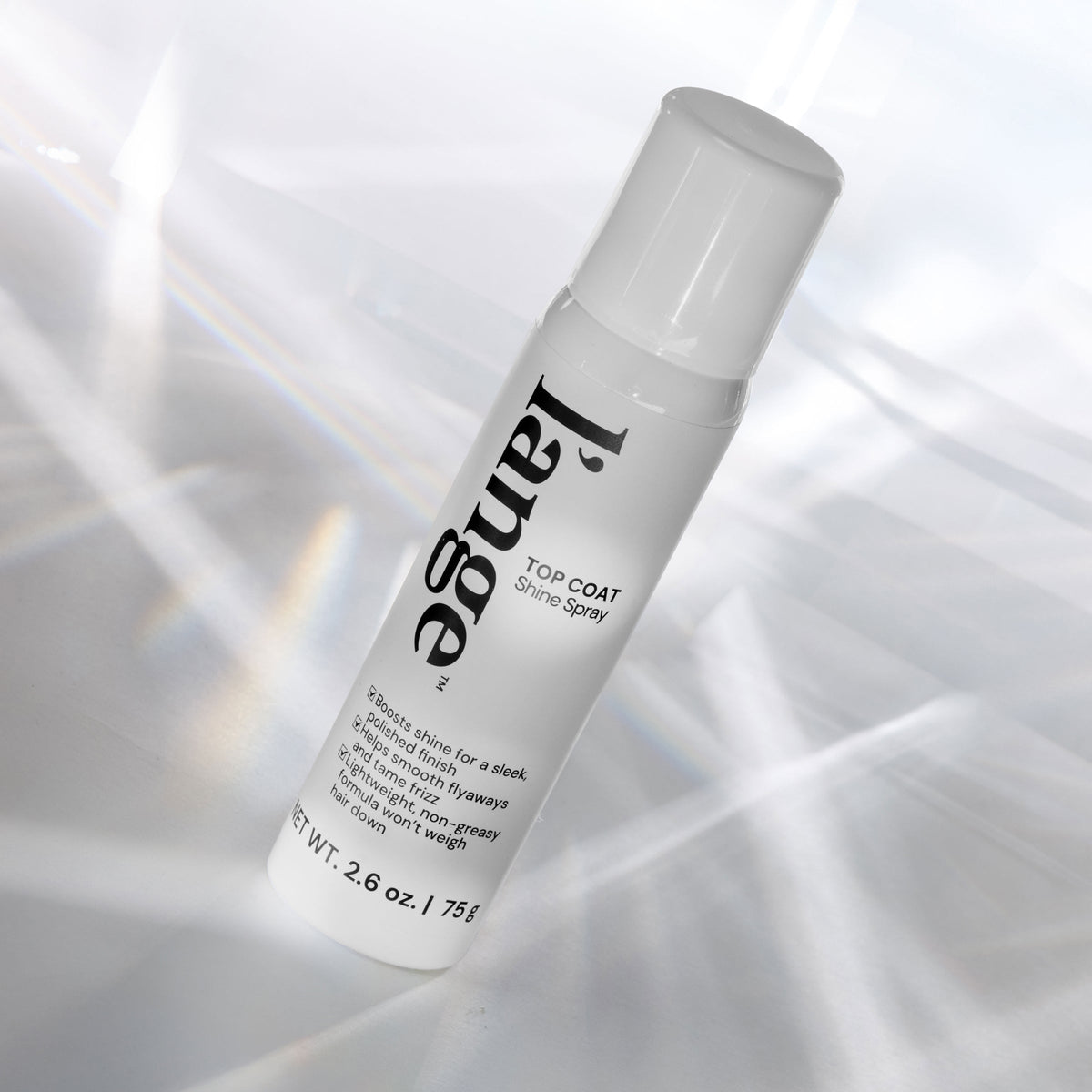L'ange Top Coat Shine Spray bottle angled on a reflective surface with light prism effects.