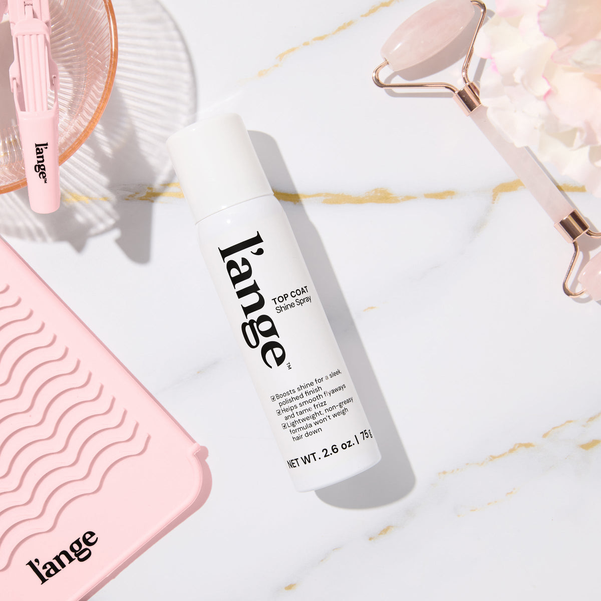 L’ange Top Coat shine spray on a vanity with pink beauty products.